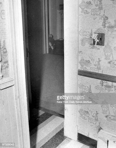 The kitchen leading into the ballroom. The body drag marks on the hallway rug are visible. The light switch also appears to be broken and held up with tape. Helen was killed at the kitchen table, while the children were killed in the back entrance off the kitchen.